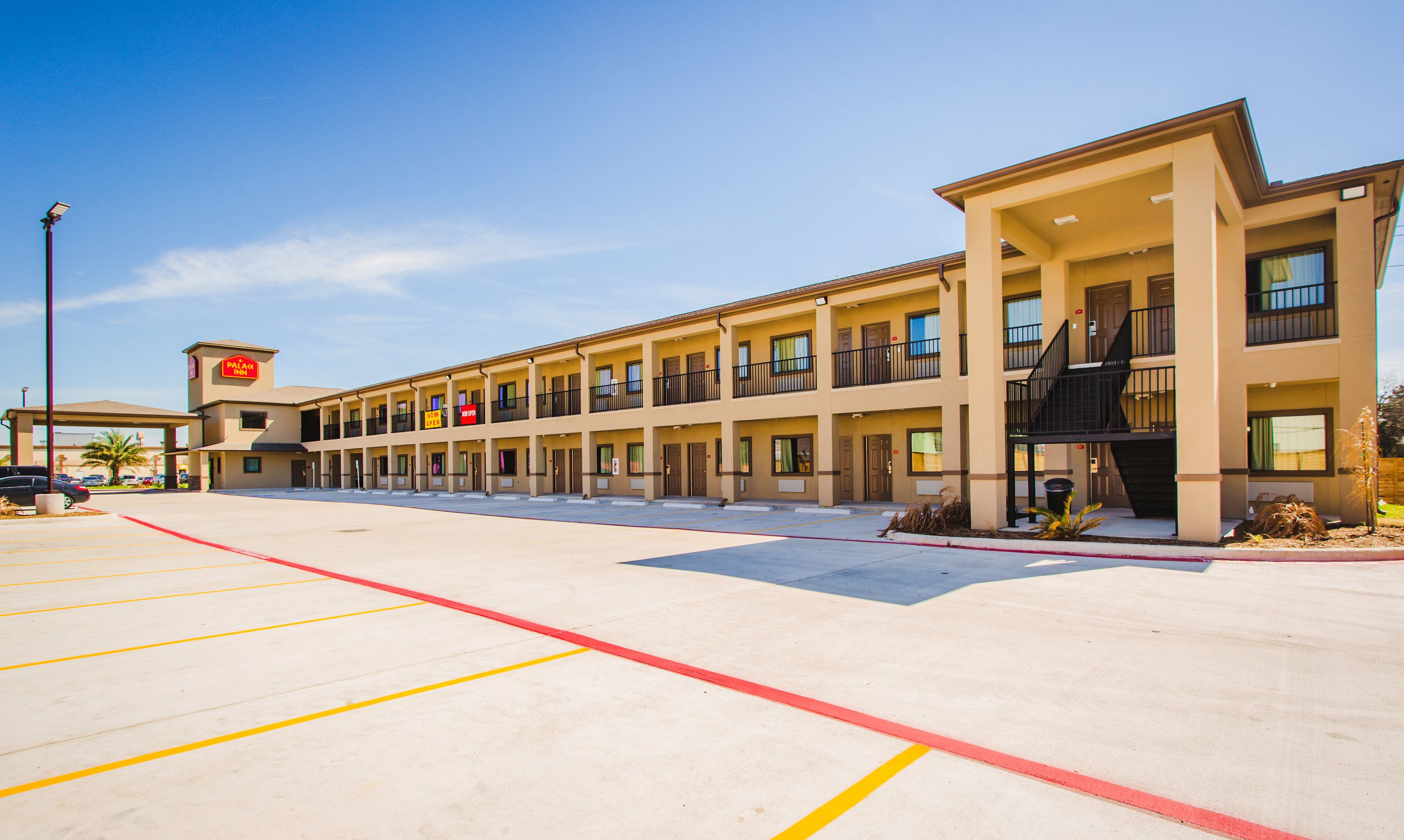 A motel with multiple floors, a parking lot, and a sign indicating availability.