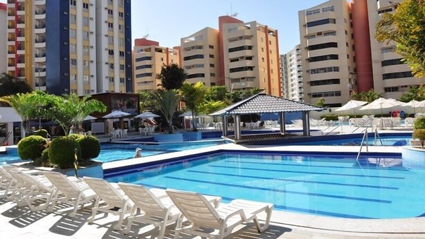 Una piscina con sillas de descanso y un pabellón, rodeada de edificios residenciales altos.