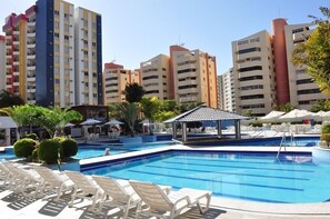 A swimming pool with lounge chairs and a gazebo, surrounded by tall residential buildings. - Temporada Eldorado Park Caldas Novas (Caldas Novas)