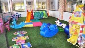 Un área de juegos interior con un tobogán, juguetes inflables y un tapete de juego.