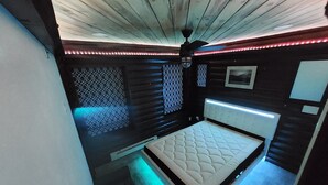 A bedroom with a bed, a ceiling fan, and patterned walls.