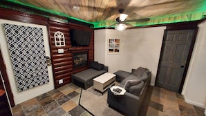 A living room with a fireplace, a television, a sofa, and a ceiling fan.