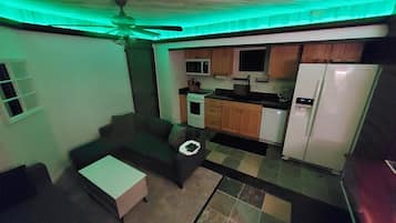 Cocina compacta con refrigerador, microondas, estufa y lavabo. Cuenta con un pequeño comedor con mesa y sillas.