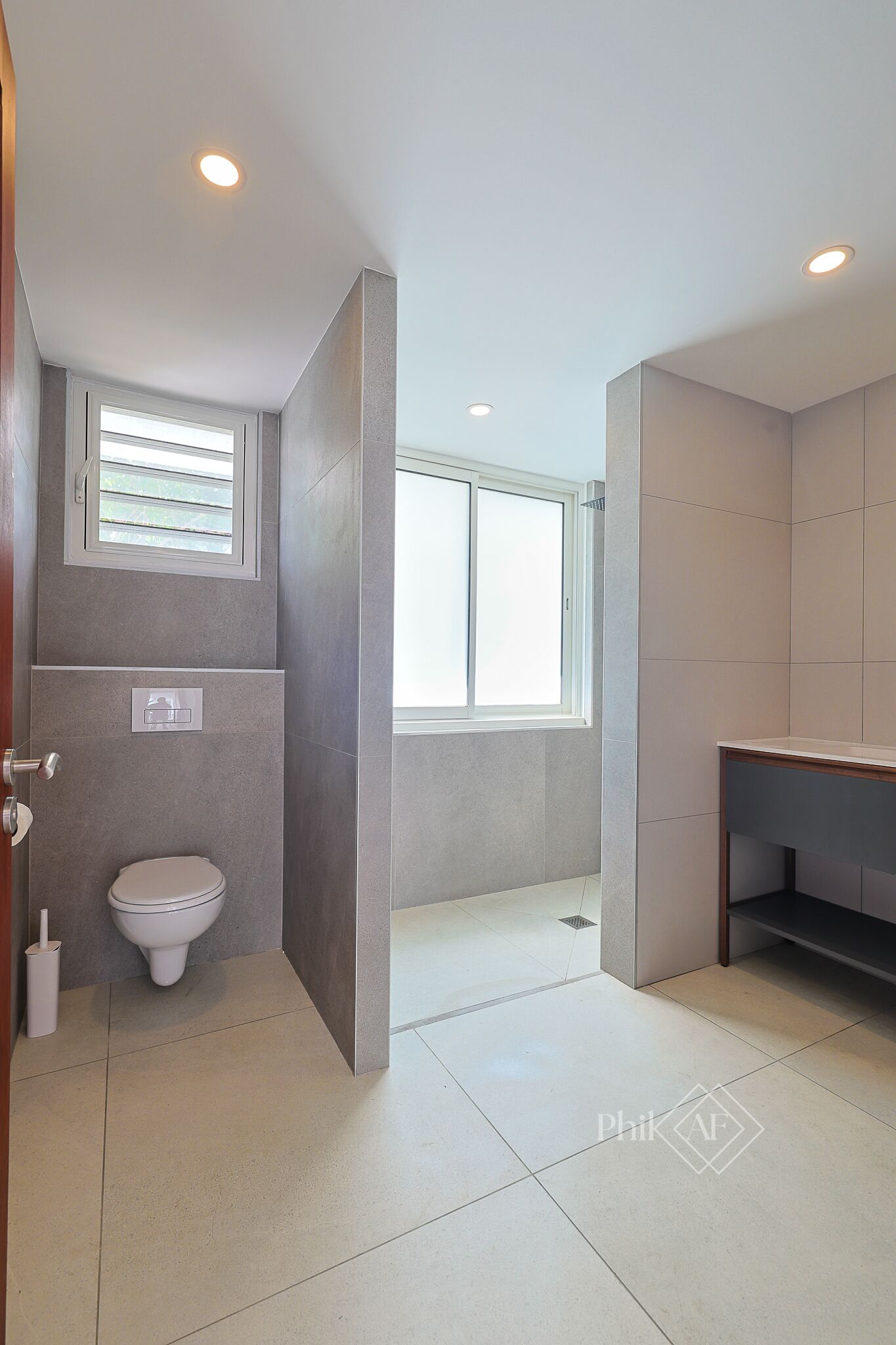 A modern bathroom with a toilet, a window, and a shower area.