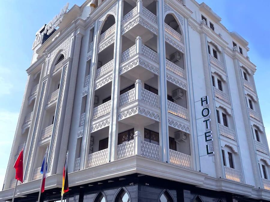 A multi-story hotel with a white facade, multiple balconies, and a sign indicating it is a hotel.