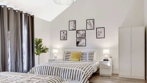 Een slaapkamer met twee bedden, een nachtkastje, een lamp, een kledingkast en wanddecoratie.