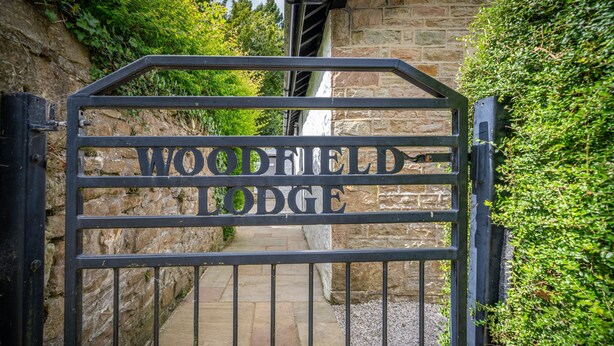 En smidesjärnsport med inskriptionen ”WOODFIELD LODGE” skrivet med versaler.
