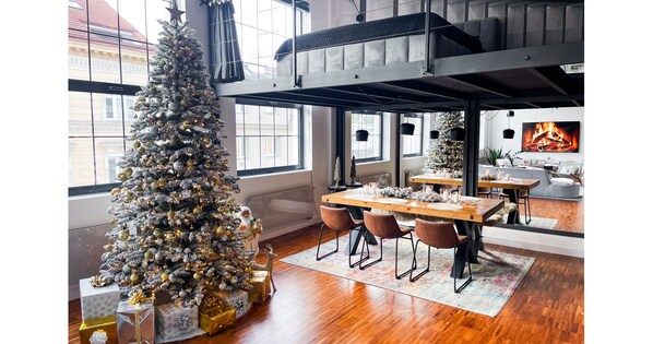 A modern dining area with a large wooden table, multiple chairs, and a Christmas tree.