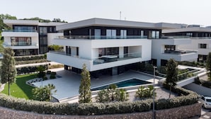 Un moderno edificio residencial de varios pisos con piscina y jardín ajardinado.