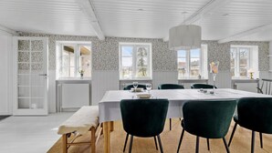 A dining area with a white table, green chairs, and a hanging light fixture. - Cozy home in Sydals with sauna (Sydals)