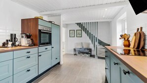 A modern kitchen with a built-in oven, a coffee machine, and a wooden cabinet. - Cozy home in Sydals with sauna (Sydals)