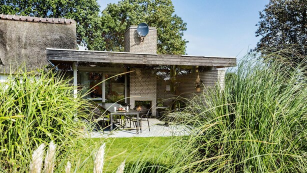 A modern house with a brick exterior, a chimney, and a patio area with a table and chairs. - Cozy home in Sydals with sauna (Sydals)