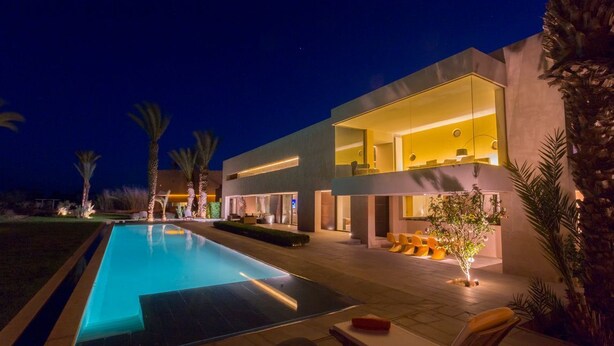 Una casa moderna amb piscina, zona d'estar exterior i espais ben il·luminats.