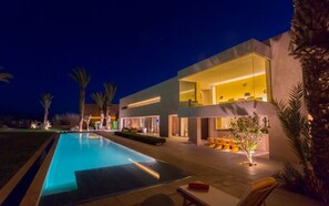 Una casa moderna con piscina, mobiliario exterior e iluminación agradable.