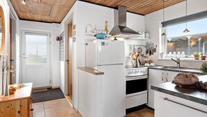 Una cucina moderna con mobili bianchi, un frigorifero Bosch, una cappa aspirante in acciaio inossidabile e una finestra che si affaccia sulla strada.