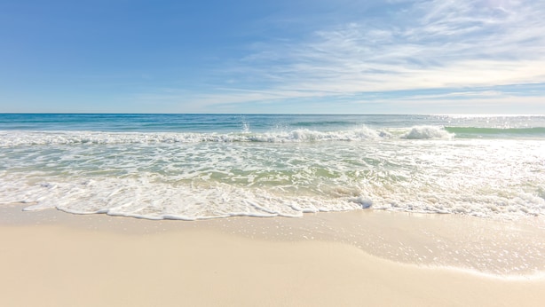 A beach with clear blue water and a sandy shore.