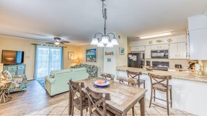 A spacious living area with a dining table, chairs, and a kitchen with modern appliances.
