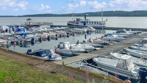 Un port de plaisance où sont amarrés différents types de bateaux, dont un petit bateau doté d’une cabine, et une jetée qui s’avance dans l’eau.