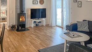 Un salon avec une cheminée, un téléviseur à écran plat, un canapé et une petite table.
