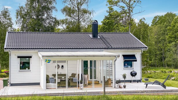 Une maison moderne dotée d’un porche abrité, de grandes fenêtres et d’une cheminée.