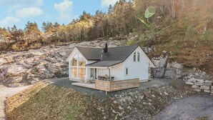 A white house with a sloped roof, large windows, and a wooden deck. - 4 bedroom amazing home in Skånevik (Skånevik)