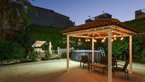 Eine überdachte Terrasse im Freien mit Whirlpool, Sitzgelegenheiten und Lichterketten.