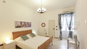 Ein Schlafzimmer mit Bett, Nachttisch, Kommode und Schreibtisch mit Stuhl.