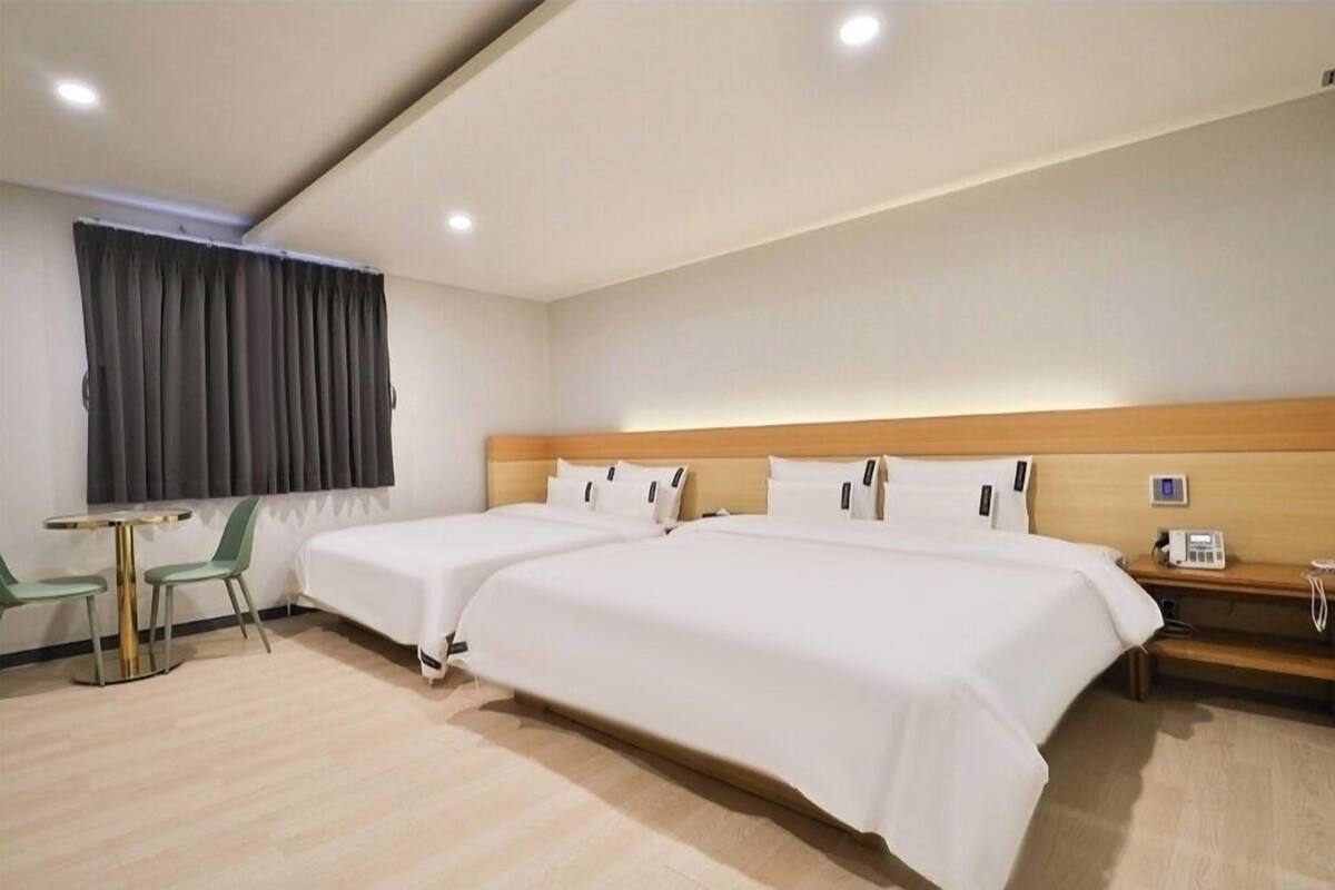 A hotel room with two beds, a small table, and chairs.