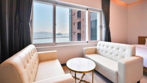 A hotel room with a large window, two white sofas, a small round table, and a bed. - Hotel 701 (Changwon)