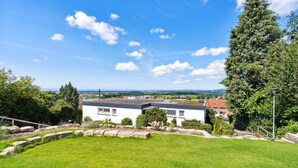 A white building with a sloped roof, surrounded by a well-maintained lawn and stone edging. - Lovely apartment in Tettnang with WiFi (Tettnang)