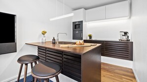 Une cuisine moderne dotée d’un îlot central, de tabourets de bar, d’un four encastré et d’une machine à café.