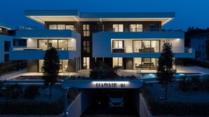 A modern, multi-story residential building with a well-lit entrance and a visible garage labeled "HADRIE D1".