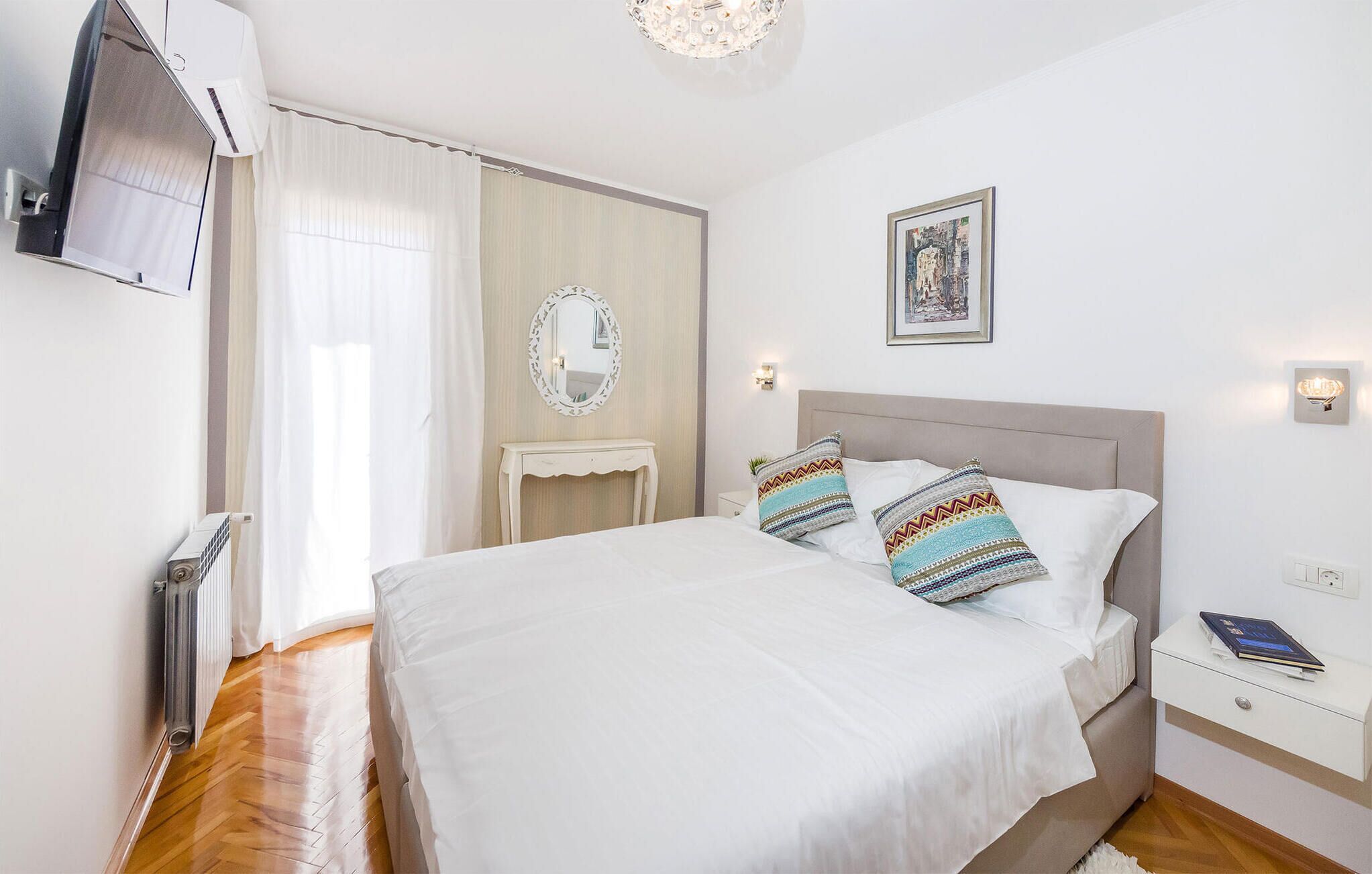 Ein Schlafzimmer mit einem Bett, einem Nachttisch und einem an der Wand befestigten Spiegel.