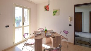 Un comedor con una mesa de madera, cuatro sillas y una botella de vino.