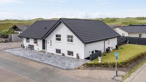 A two-story house with a dark roof, white exterior walls, and a small front yard.