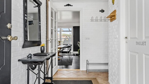 A modern bathroom with white brick walls, a black sink, and a mirror. There is a toilet visible on the right side.
