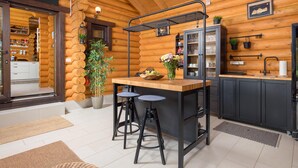 Een moderne keuken in een blokhutstijl met een houten kookeiland, barkrukken en een spoelbak.