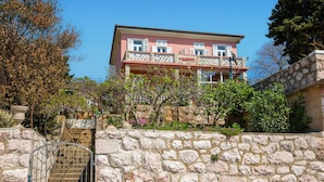 A pink building with a stone wall in front, a metal gate, and a staircase leading up. - Nice apartment in Novi Vinodolski with WiFi (Novi Vinodolski)