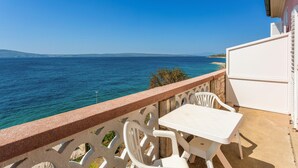 A balcony with a white table and chairs overlooking a coastal view. - Nice apartment in Novi Vinodolski with WiFi (Novi Vinodolski)