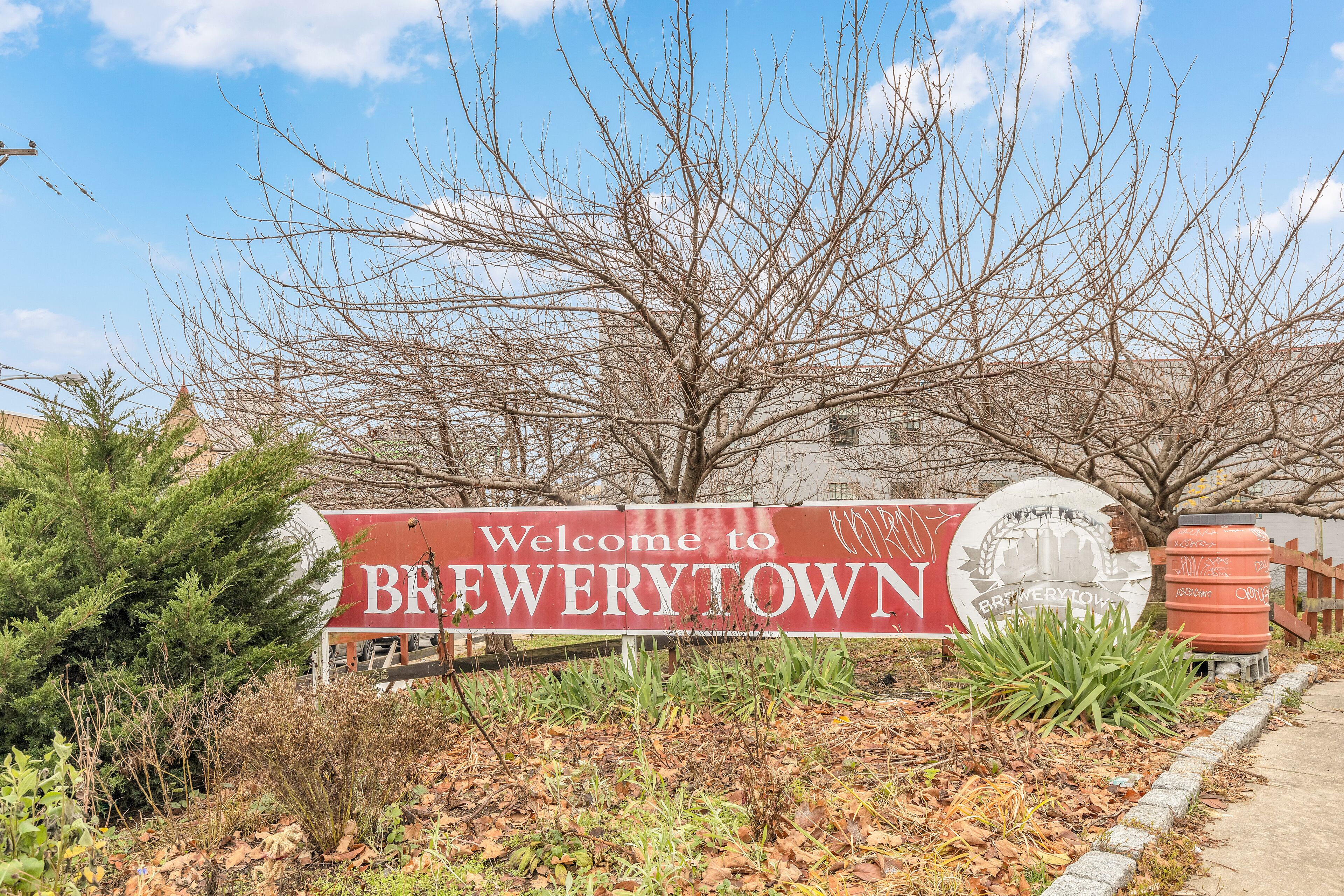A welcome sign for Brewertown with a clear sky and leafless trees in the background.