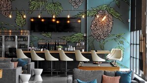 A modern bar area with a counter, bar stools, and a television screen.
