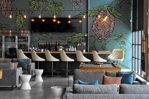 A modern bar area with a counter, bar stools, and a television screen.