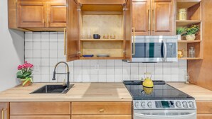 A kitchen with wooden cabinets, a microwave, a stove, and a sink.