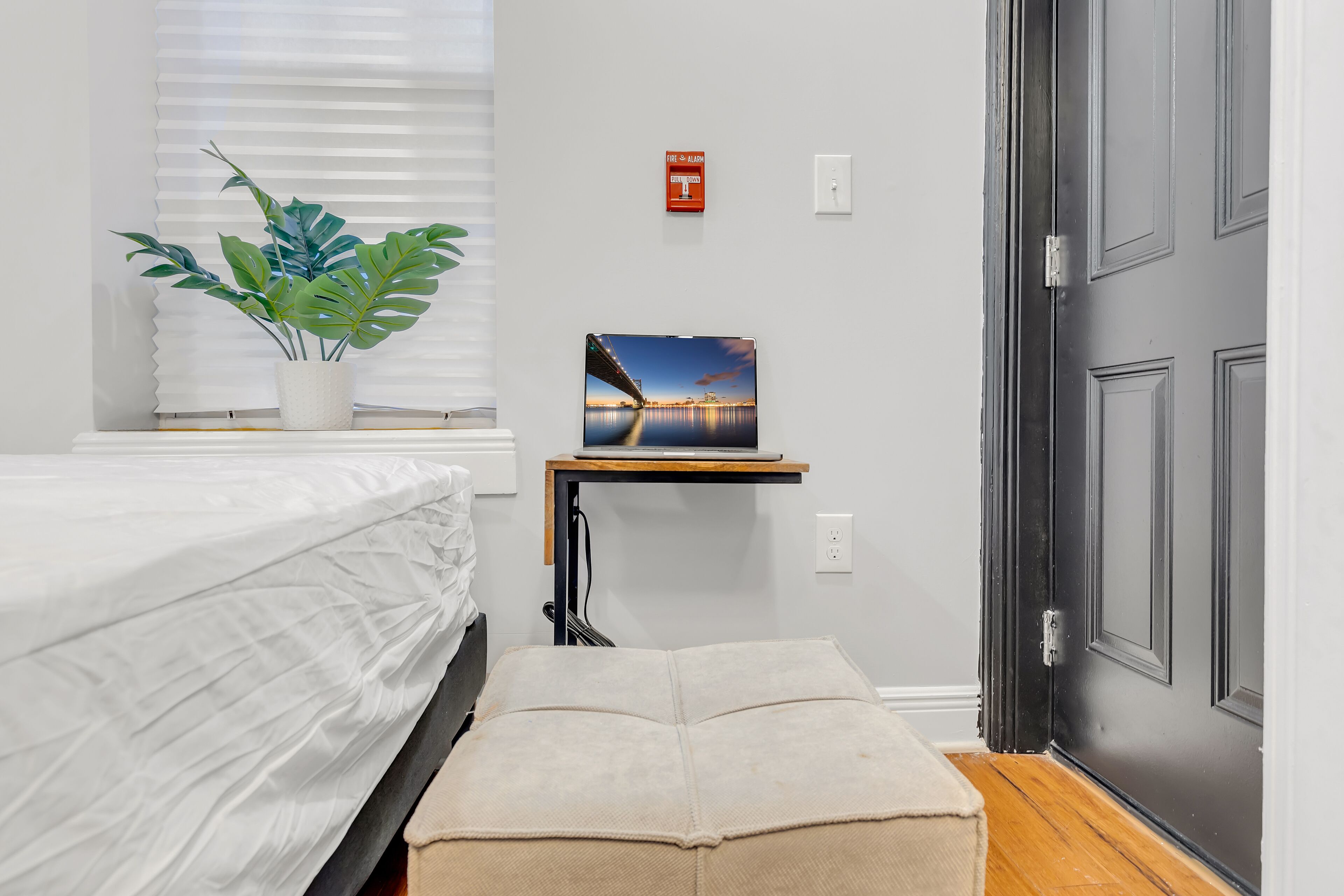Una camera da letto ordinata con un letto, una pianta sul comodino e un tavolino con un quadro.