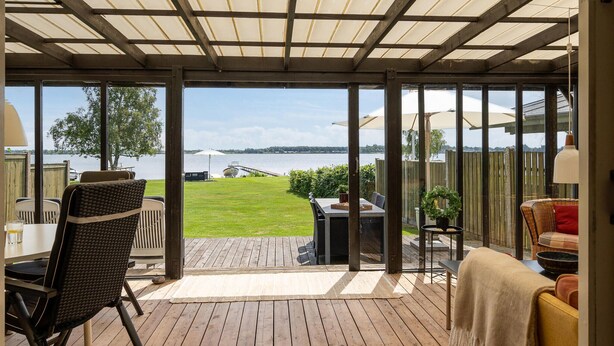 A covered patio with a view of a lake, outdoor furniture, and a barbecue area. - Amazing home in Sunds with lake view (Sunds)