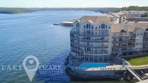 A multi-story hotel with balconies, a swimming pool, and a waterfront view.