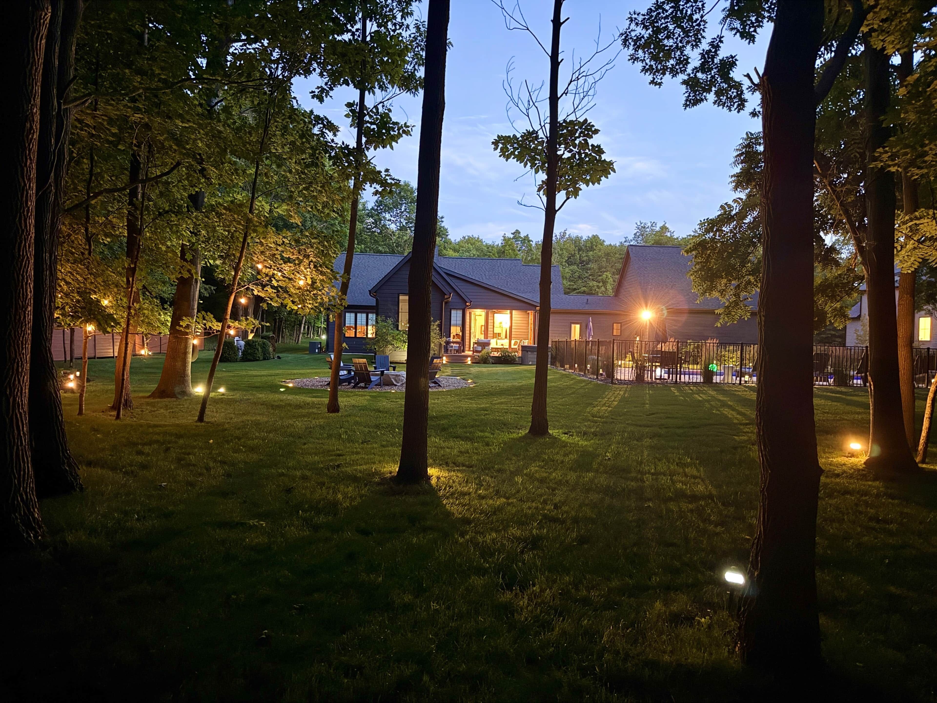 A residential property with a well-maintained lawn, a patio area with seating, and a house with large windows.