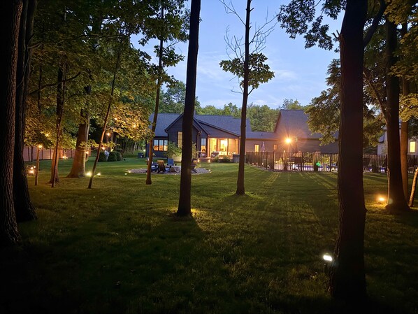 A residential property with a well-maintained lawn, a patio area with seating, and a house with large windows.
