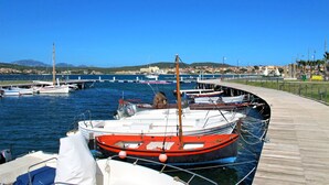 Ein Yachthafen mit verschiedenen Schiffen, einer hölzernen Anlegestelle und einem strahlend blauen Himmel.