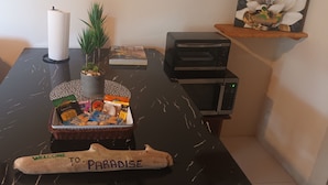 Un comptoir de cuisine avec un panier de collations, un grille-pain, un four à micro-ondes, une bougie et un panneau d’accueil.